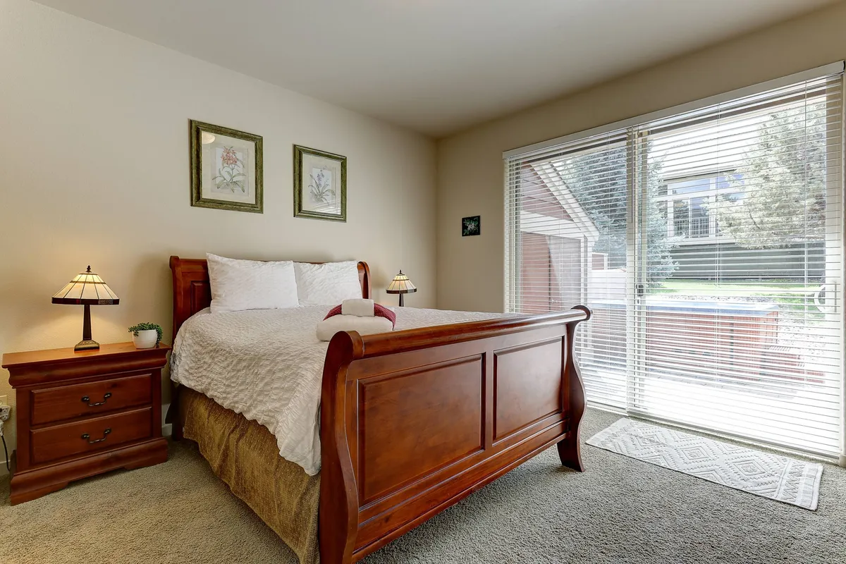 This image features a serene bedroom scene with a plush bed, nightstand, soft lamp lighting, and a window letting in gentle morning light. The overall ambiance is tranquil and restful, ideal for conveying comfort and relaxation.