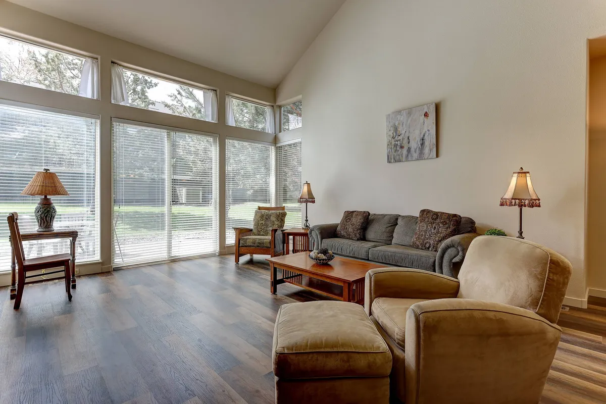 A cozy living area with a comfortable sofa, large windows streaming in natural light, a coffee table, and inviting armchairs creates the perfect spot for restful evenings or accommodating extra guests on the queen sofa bed.