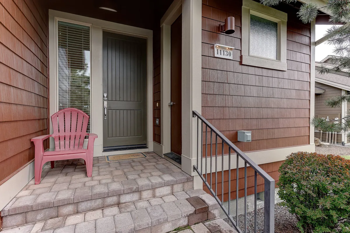 A welcoming exterior view of a townhouse front door, complete with a pink chair on the porch and steps leading up. The inviting porch suggests a comfortable base from which to enjoy both seasonal festivities and daily adventures.
