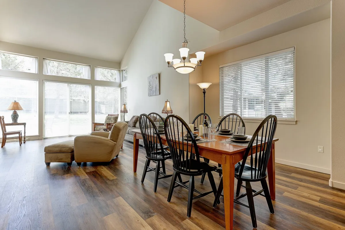 A sunlit dining area with a table set for a meal, comfortable armchair, and large windows bringing in natural light—ideal for shared meals, morning coffee, or board games bathed in sunshine.