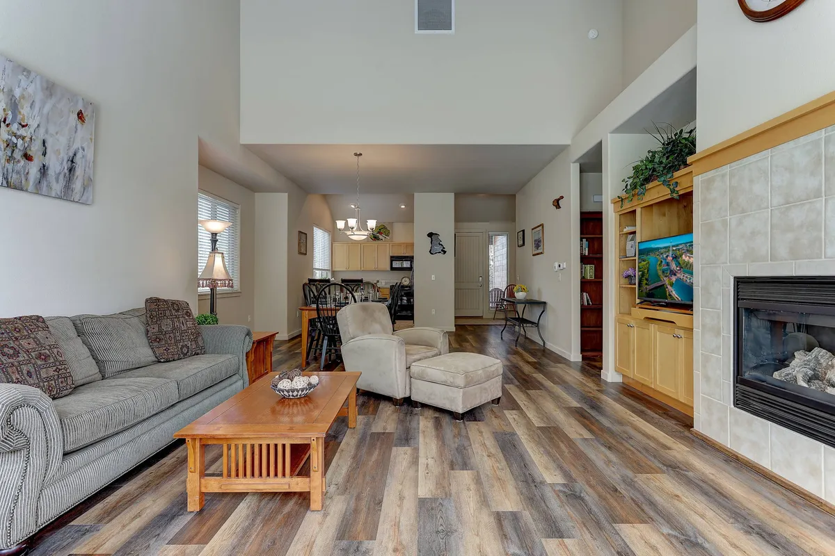 The hero image showcases a warm, inviting open-concept living area with a plush sofa, a glowing fireplace, a stylish coffee table, and a seamless flow into the dining area and modern kitchen—perfect for relaxing, entertaining, and enjoying time with friends or family.